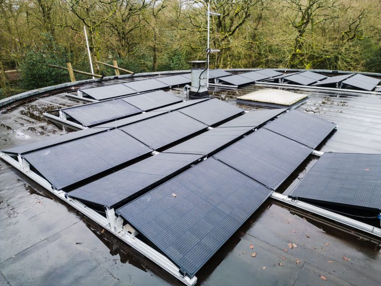 Eco Invest Brasil aprova R$ 49,95 bilhões para inovação e transformação ecológica Painéis solares instalados no telhado de uma edificação, cercados por vegetação.